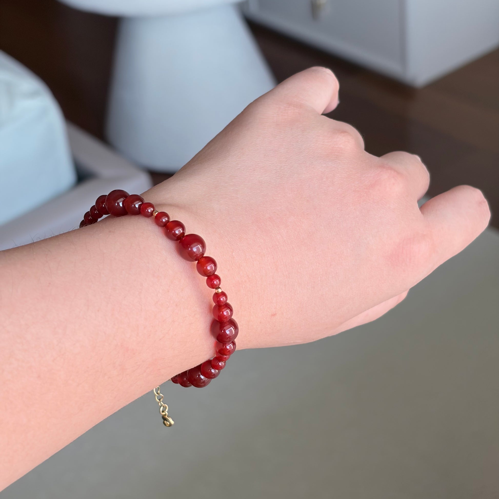 Red Agate Ember Line Bracelet worn on the wrist, a slim Fire element red agate bracelet with mixed bead sizes, gold-tone details, and an adjustable chain.