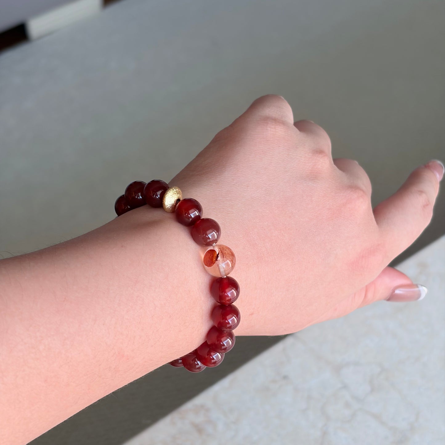 Red Agate Solar Ember Bracelet worn on the wrist in soft natural light, a Fire element red agate bracelet with a gold-toned accent for warm everyday styling.