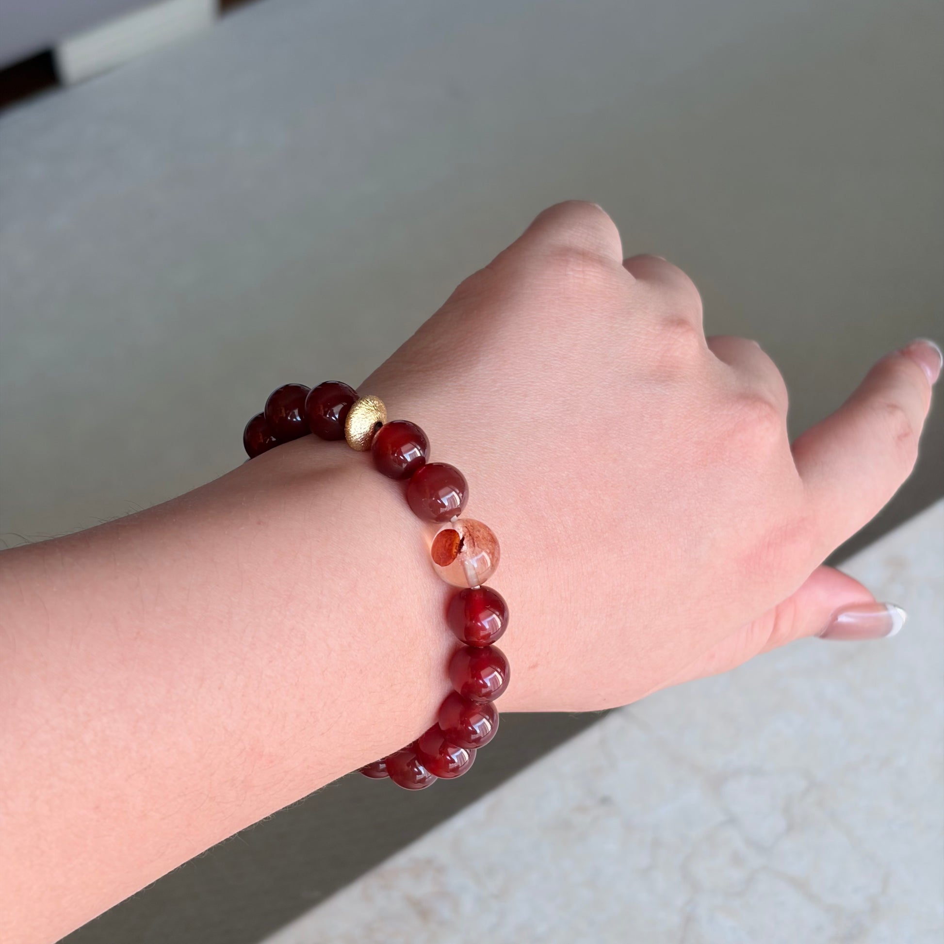 Red Agate Solar Ember Bracelet worn on the wrist in soft natural light, a Fire element red agate bracelet with a gold-toned accent for warm everyday styling.