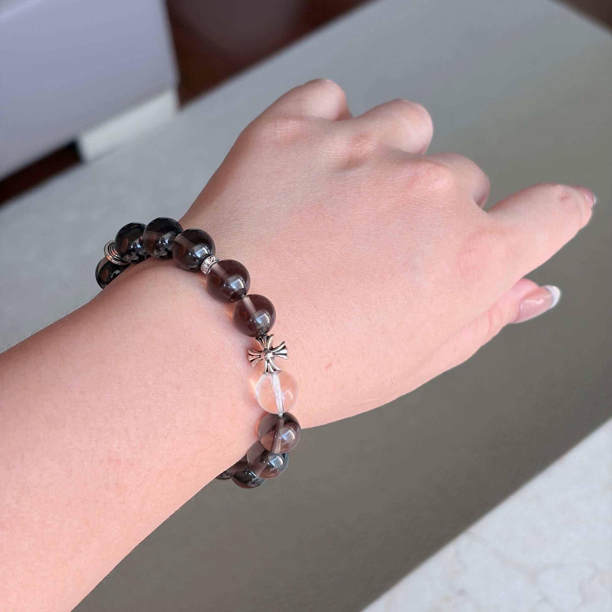 Smoky Quartz Still Smoke Bracelet worn on the wrist in a neutral home setting, an Earth element smoky quartz bracelet with tea-brown translucency and silver-toned details.