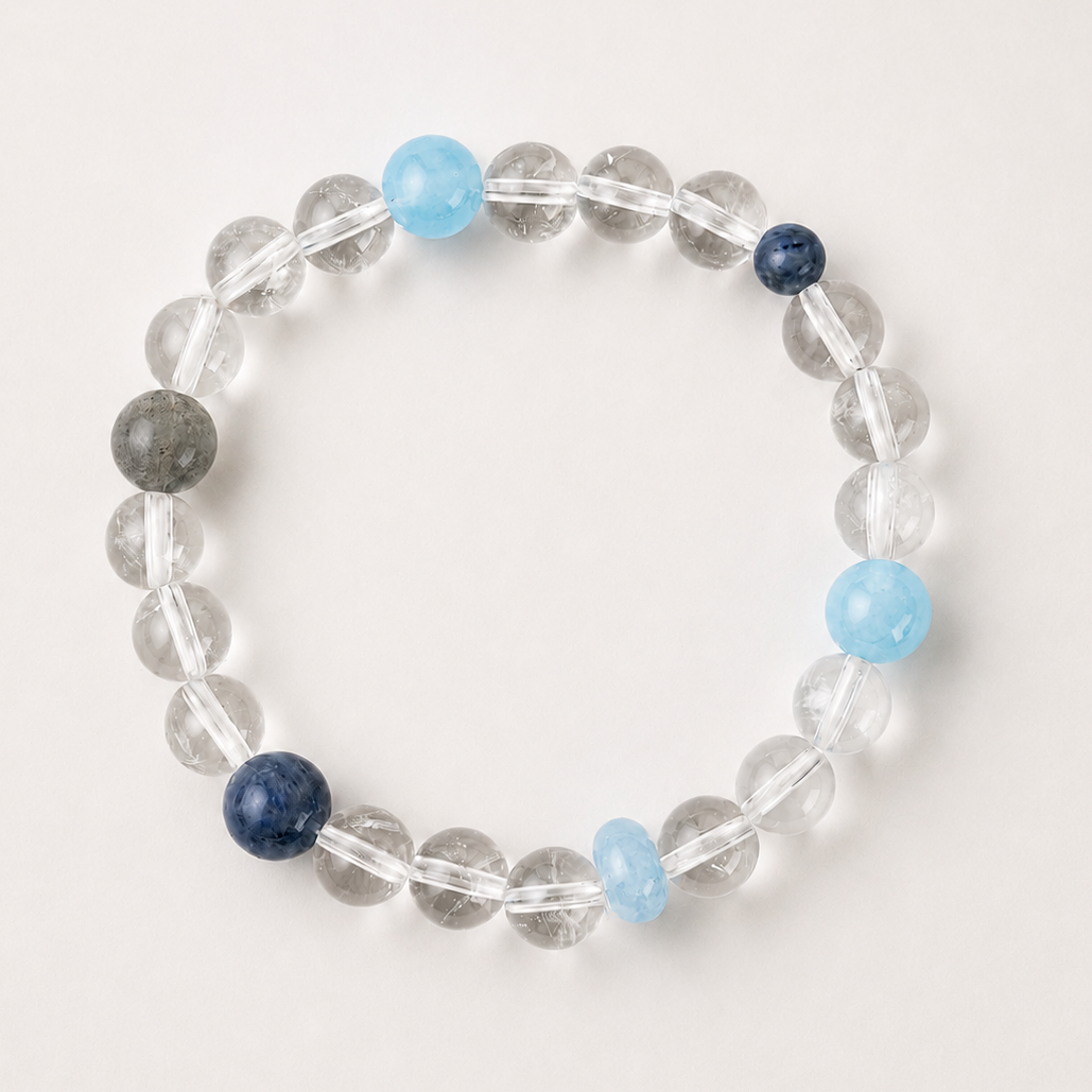Clear quartz, grey moonstone, and blue kyanite Water element bracelet on a soft light gray background.