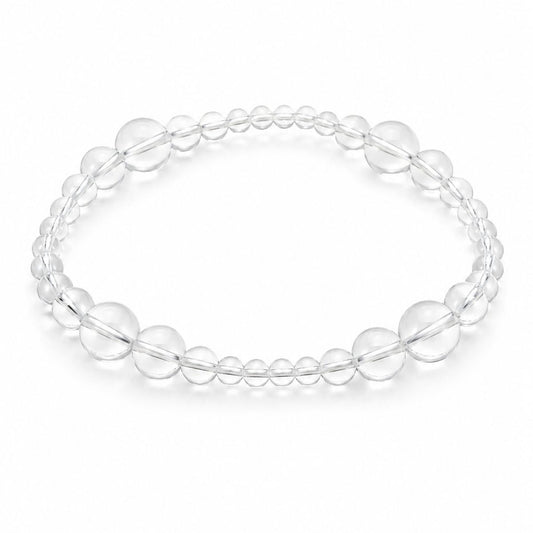 Clear Quartz Silver Veil Bracelet styled beside a clear quartz charm bracelet on textured stone in soft natural light.