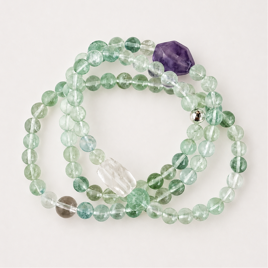 Green fluorite, clear quartz, and amethyst multi-wrap bracelet on a soft light gray background.