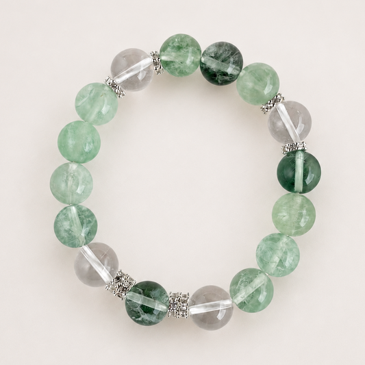 Green fluorite and clear quartz beaded stretch bracelet with silver-toned spacer details on a soft light gray background.
