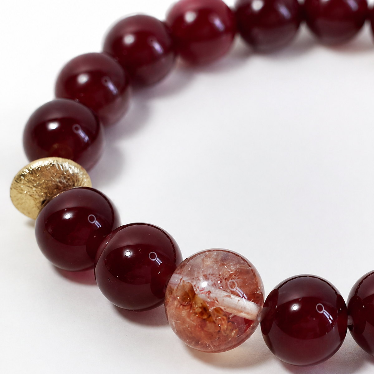 Close-up of glossy red agate beads and gold-toned accent on Veyra Grove bracelet