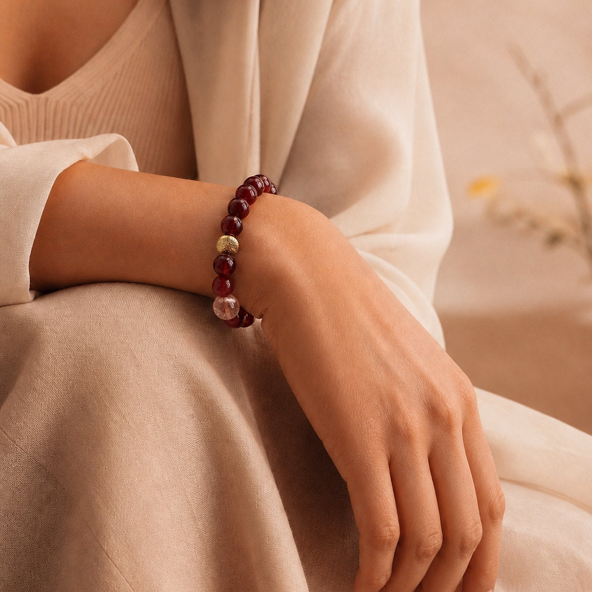 Red agate bracelet worn on wrist with soft beige neutral styling