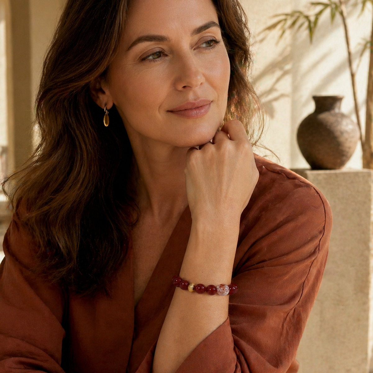 Red agate bracelet worn with warm earth-toned styling and soft natural light