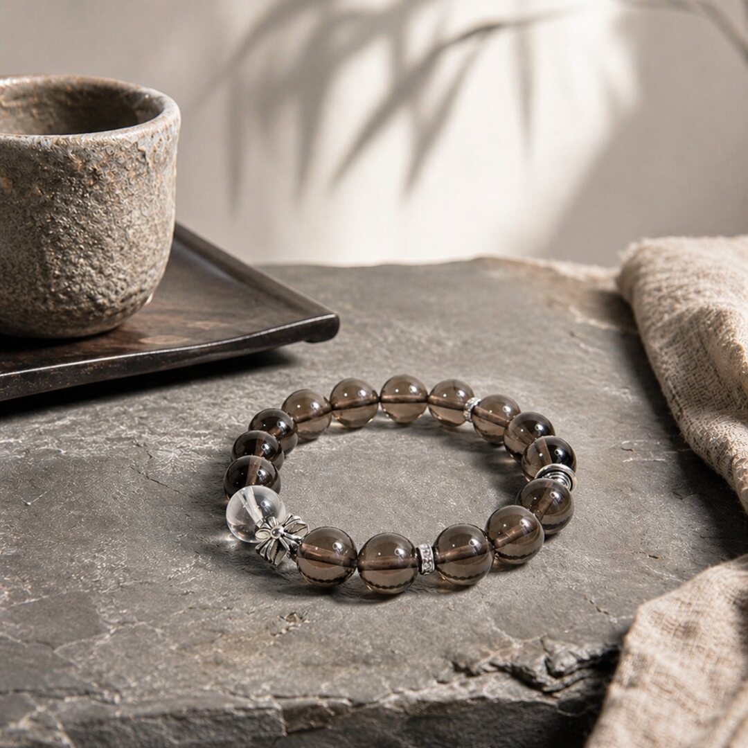 Smoky quartz bracelet styled on natural stone with tea cup and soft shadow by Veyra Grove